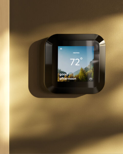 Smart thermostat on a warm-toned wall showing 72 degrees