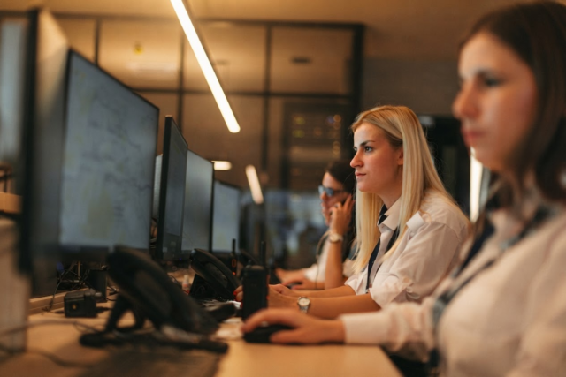 Two remote monitoring operators reviewing live video alerts at a workstation
